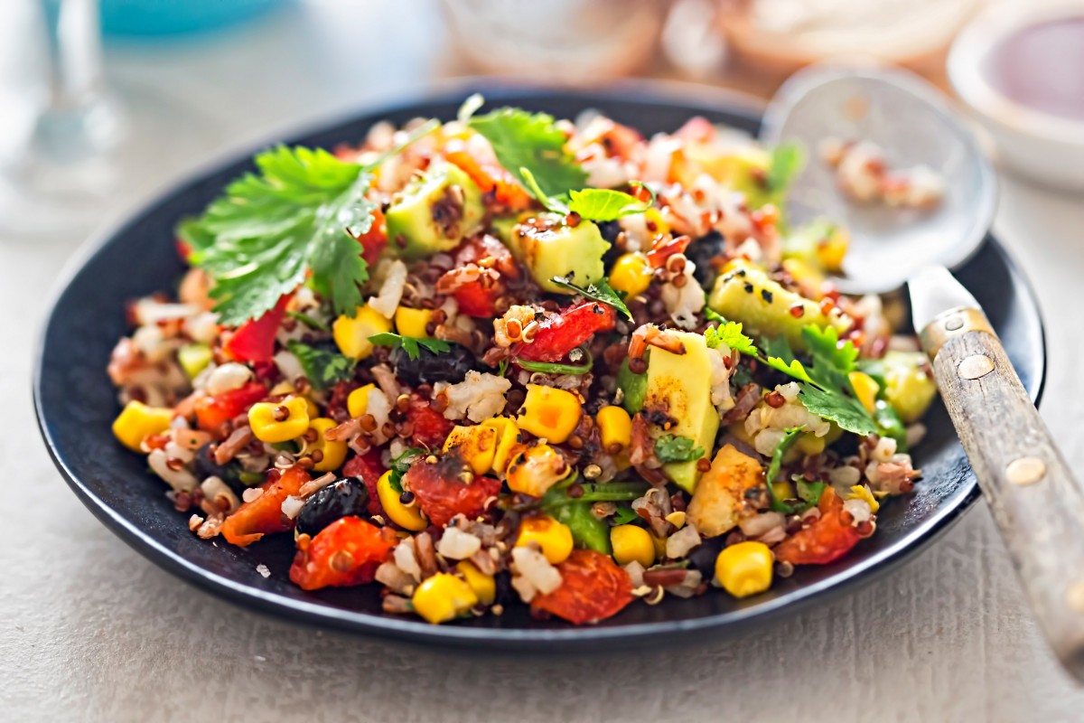 Lekker gevulde mexicaanse rijstschotel met quinoa, avocado, mais, kidneybonen en tomaat